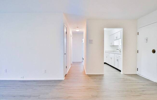 an empty living room with white walls and wood floors
