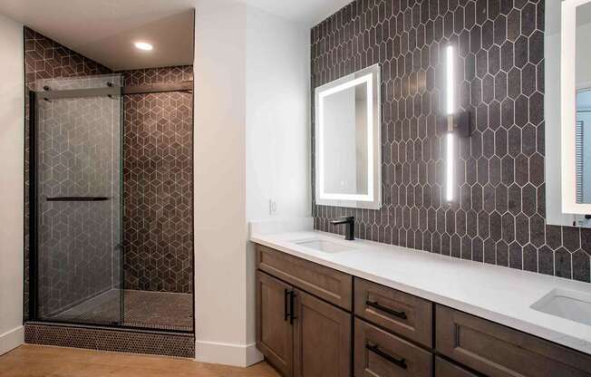 A bathroom with a brown tile shower and a white sink.