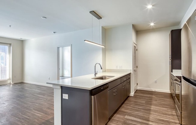an empty kitchen with stainless steel appliances and wood flooring