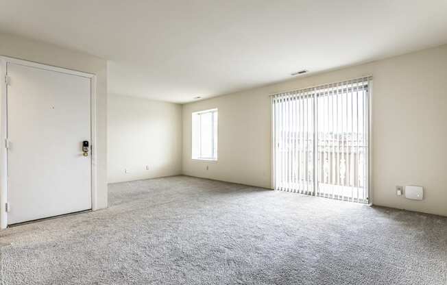 an empty living room with a door to a balcony