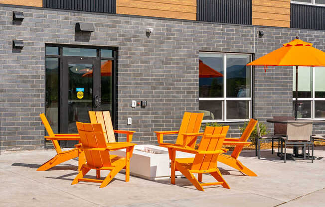 A set of orange chairs and a table are placed on a patio.