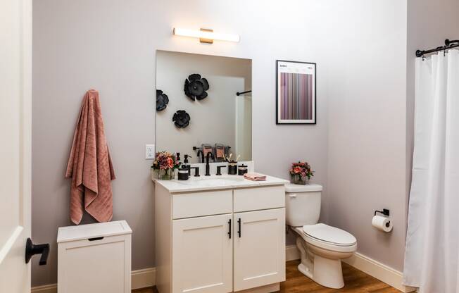 a bathroom with a white sink and toilet next to a white shower curtain and a pink towel