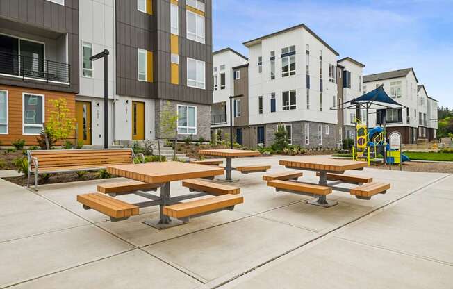 Picnic tables are set up in a courtyard between two buildings.