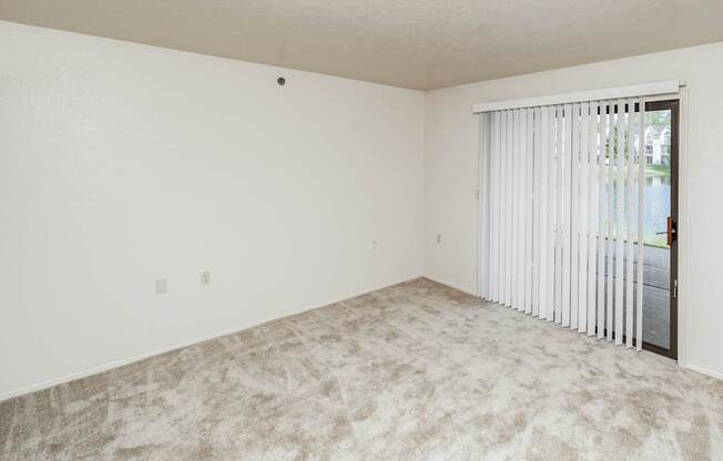 A room with a carpeted floor and a sliding glass door.