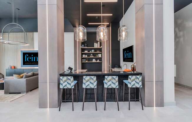 a kitchen with a bar and stools in a living room with a couch