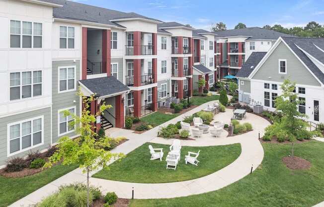Apartment complex with a green lawn and white chairs.