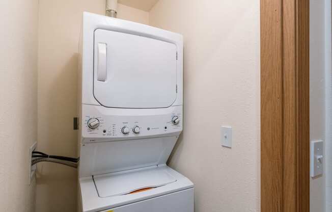 a laundry closet with a washer and dryer on top of each other. Fargo, ND Westwood Apartments