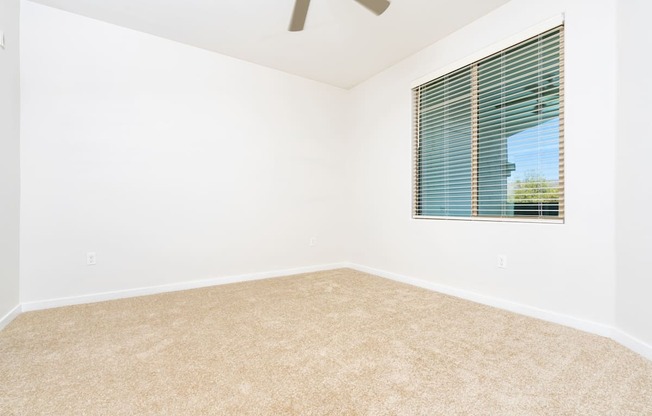 an empty room with a window and a ceiling fan