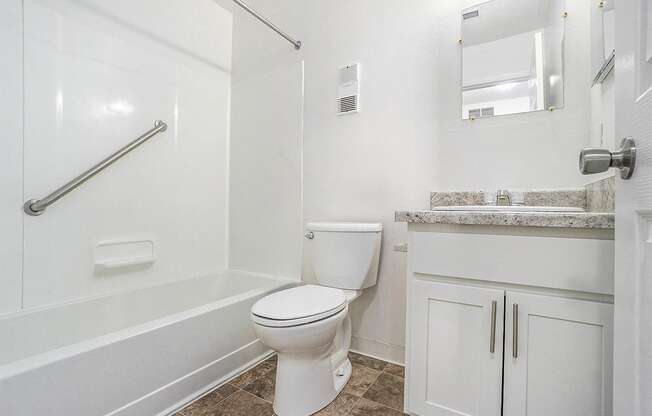 A white toilet in a bathroom with a marble counter.