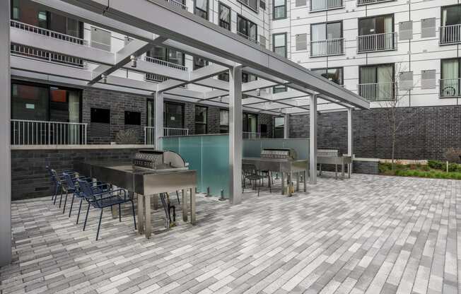 a patio with tables and chairs and a bar and grill in front of a building