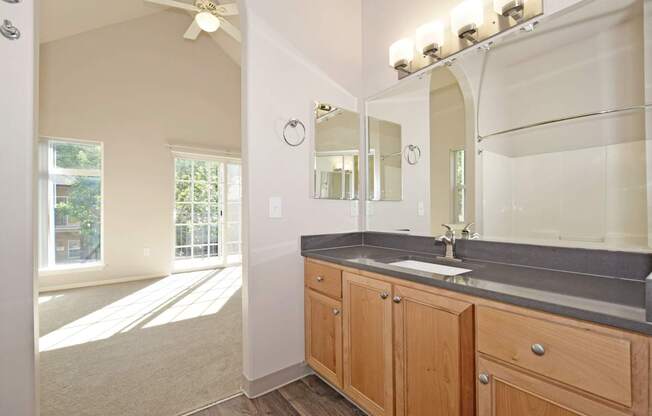 A bathroom with a sink, mirror, and a fan.