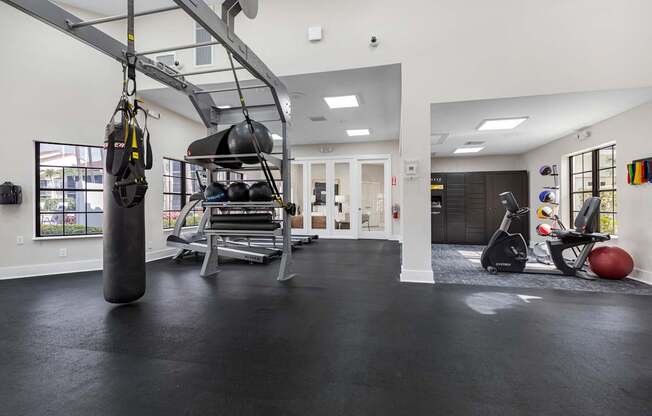 A gym with a punching bag, weights, and exercise equipment.