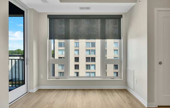 a bedroom with a large window and hardwood floors