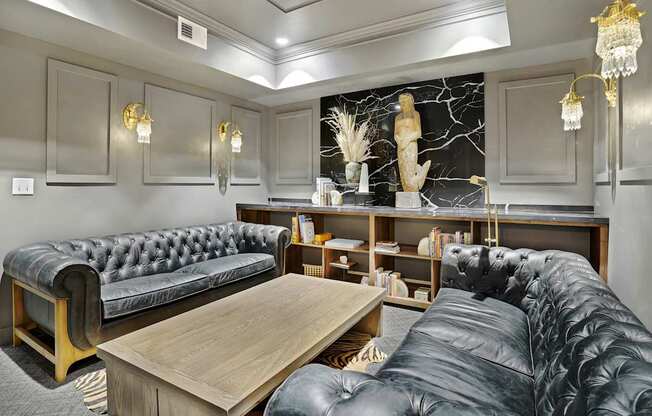 A black leather sofa sits in a well-lit room with a wooden coffee table in front of it.