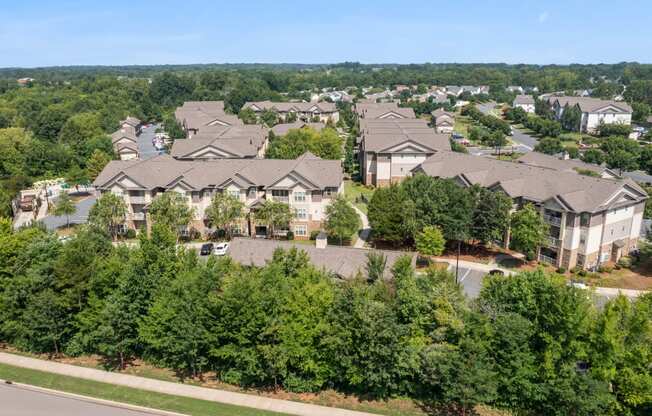 an aerial view of a large housing complex with trees in the foreground and a blue sky in