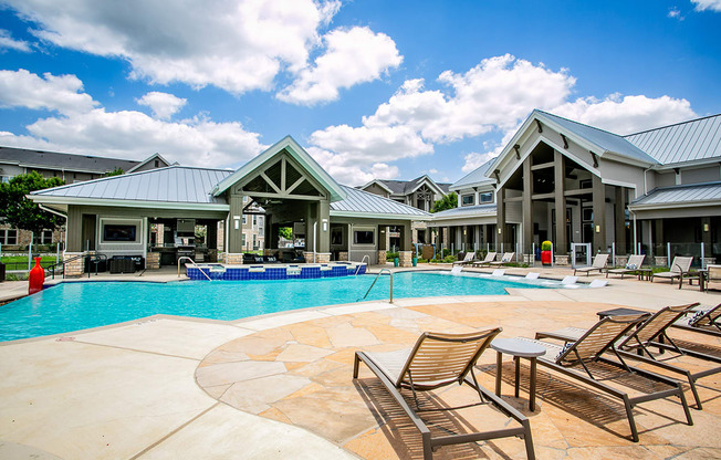 a resort style swimming pool with lounge chairs and a hot tub
