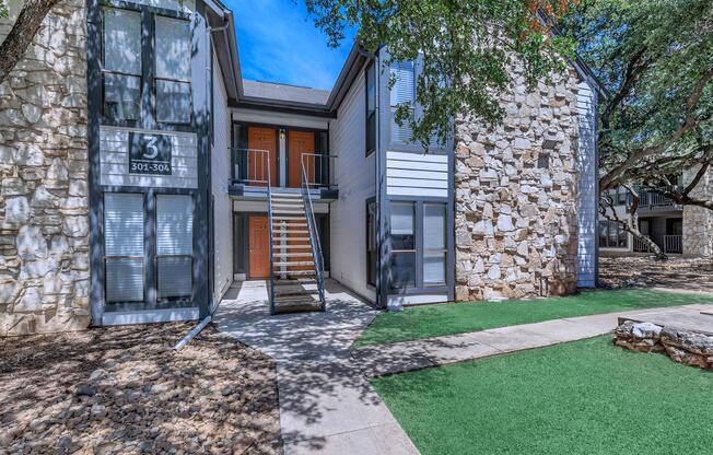 a stone building that has grass in front of a house