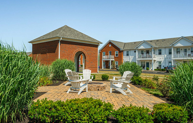 a brick patio with two chairs and a fire pit in front of a brick building