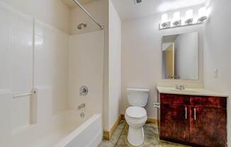 A white bathroom with a wooden cabinet and a white toilet.
