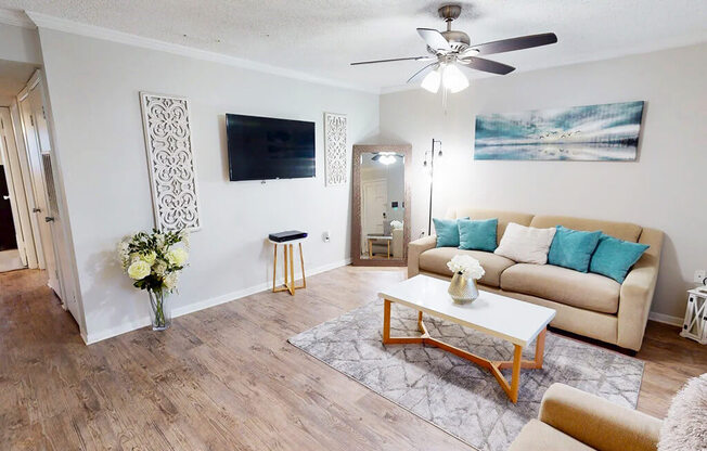 A living room with a beige couch, a wooden coffee table, and a ceiling fan.