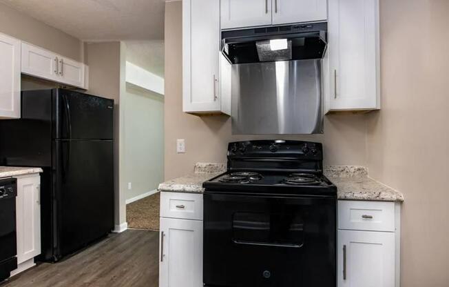 a kitchen with black appliances and white cabinets at Cleo Apartments, Alabama, 35611