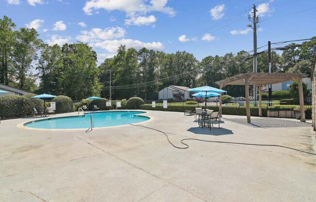 A pool with a hammock and umbrellas.