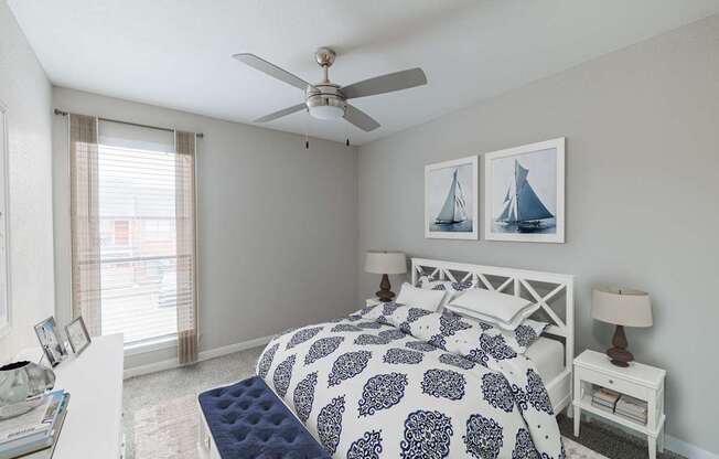A bedroom with a bed, nightstand, and a ceiling fan.
