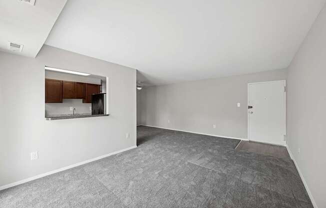 A spacious empty room with a kitchenette in the corner.