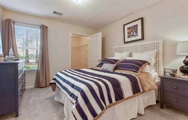 staged bedroom with carpeted flooring, window, and walk-in closet