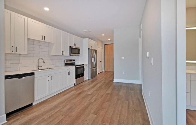 A kitchen with white cabinets and wooden floors.
