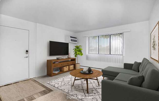 A garden style living room with a large window and carpeting at Granada Apartments, Jackson, 49202