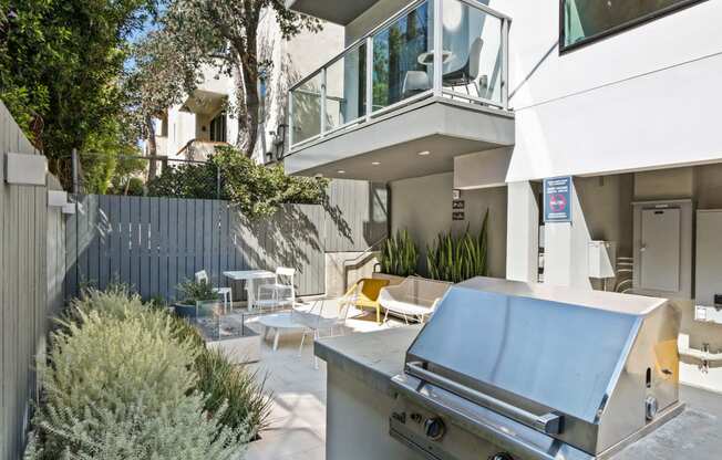 a backyard with a barbecue grill and a patio with tables and chairs