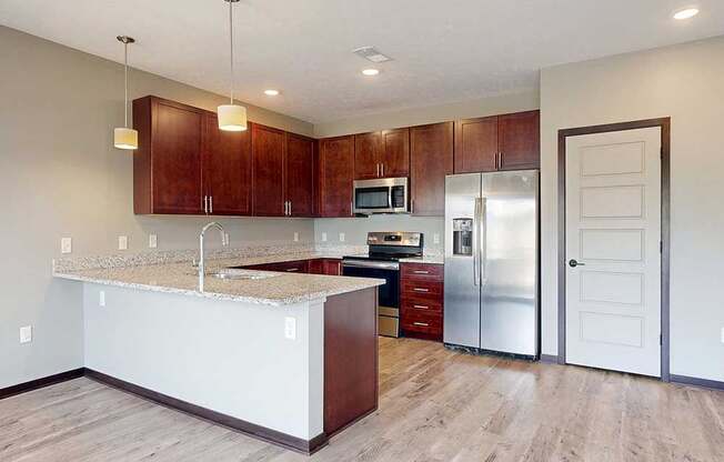 A modern kitchen with wooden cabinets, granite counters, stainless steel appliances, and a pantry to the side.