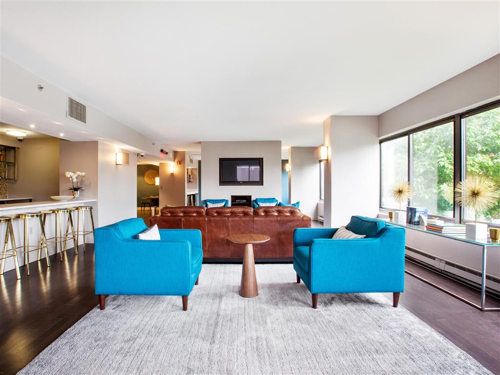 Seating area with two blue seats and a leather couch in the clubhouse at Prospect Place, Hackensack.