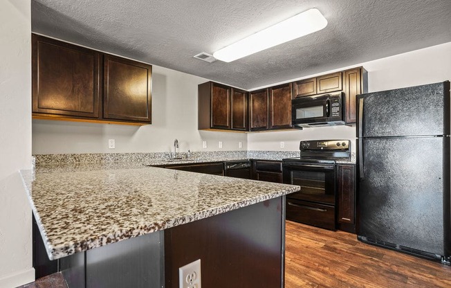 A kitchen with a granite countertop and a black refrigerator.