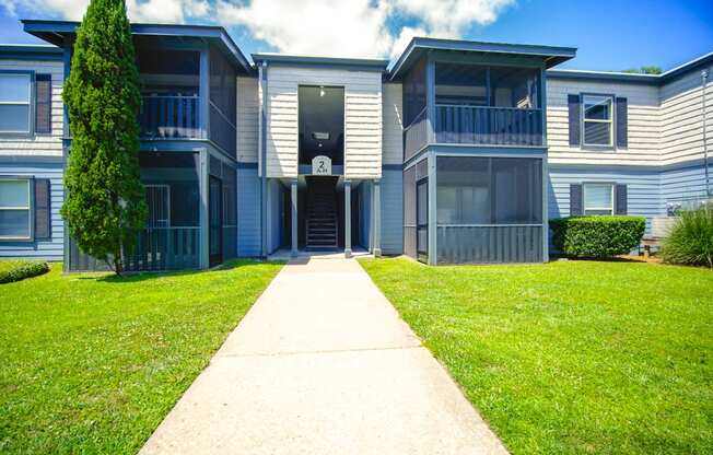 front view of an apartment building with a sidewalk and grass