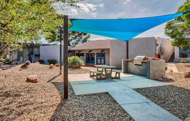 a patio with a blue canopy and a picnic table in front of a house