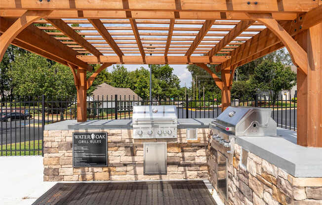 A water booth with grills and a sign that says "Grill Rules" is under a wooden pergola.