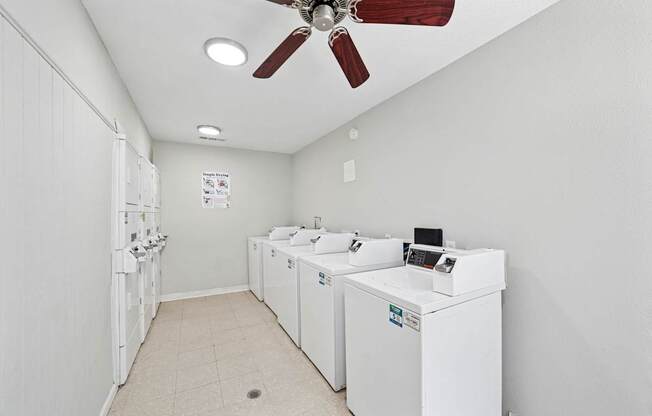 A laundry room with a fan and washing machines.