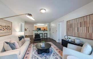 A living room with a white couch, a coffee table, and a large painting on the wall.