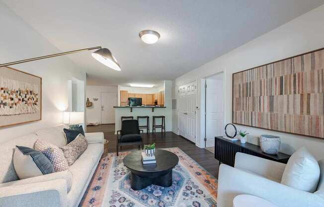 A living room with a white couch, a coffee table, and a large painting on the wall.