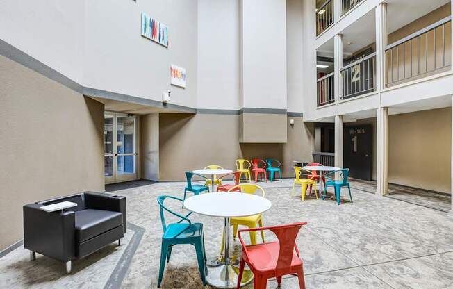 A white table surrounded by colorful chairs in a courtyard.