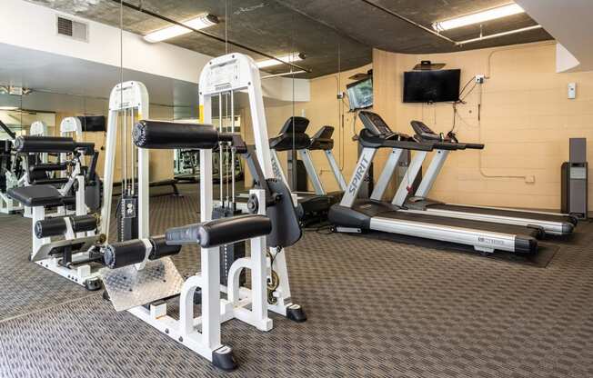 a gym with a lot of exercise equipment and a tv on the wall