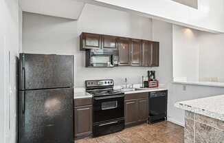 Kitchen with black appliances and brown cabinets  at Wellington Farms, Charlotte