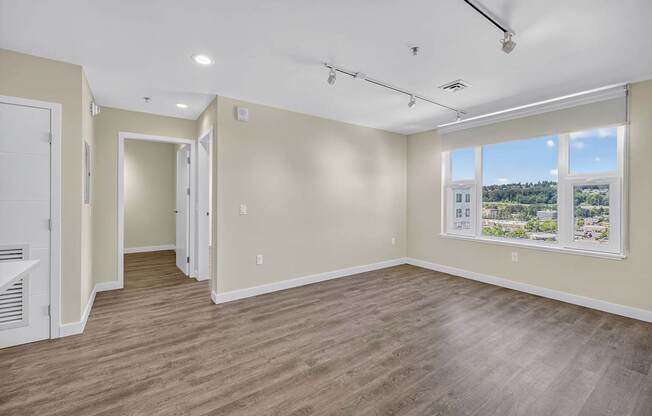 A spacious room with wooden flooring and a large window.