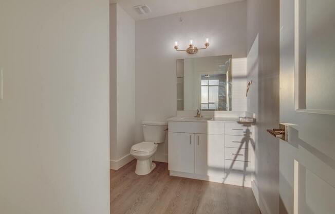 A white bathroom with a toilet, sink, and mirror.