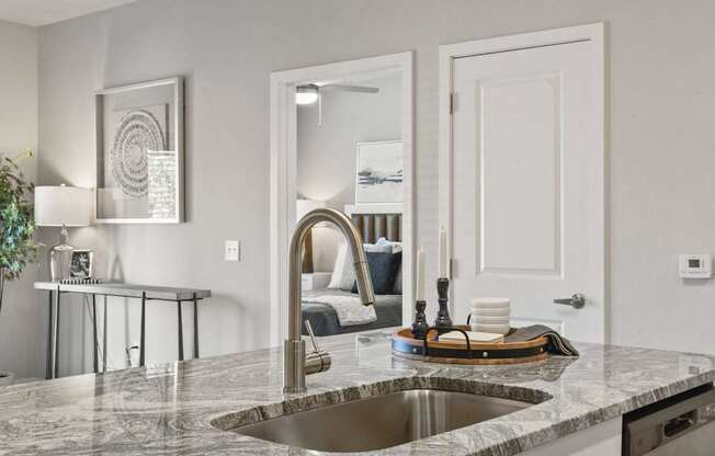 A modern kitchen with a marble countertop and a stainless steel sink.