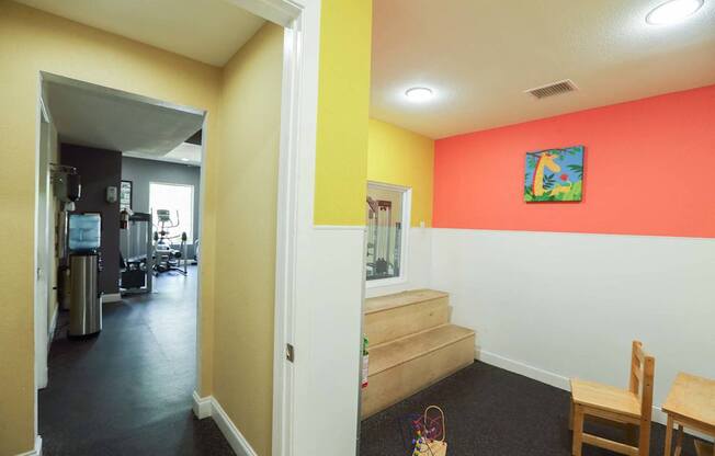 A hallway with a chair and a table in the foreground and a room with a painting on the wall in the background at Willow Creek Apartments, Texas, 77012