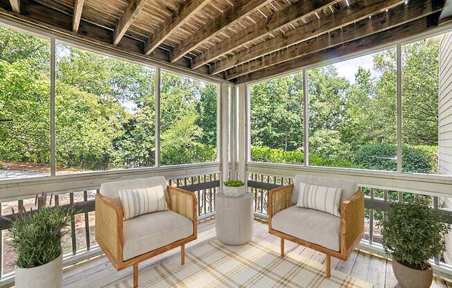 A wooden balcony with two chairs and a table.