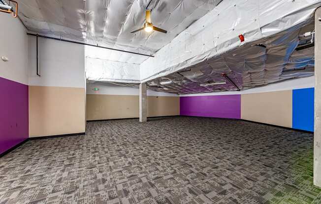 A room with a carpeted floor and a ceiling fan.